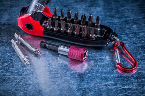 Turnscrew with interchangeable heads on scratched metallic background construction concept
