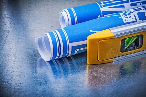 Rolled up blueprints construction level on metallic background