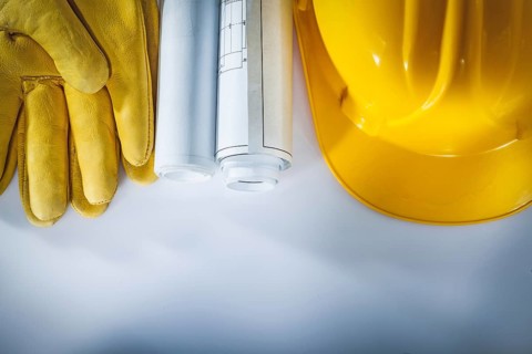 Construction drawings hard hat protective gloves on white background