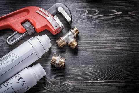 Monkey wrench copper plumbing fittings rolled up construction plans
