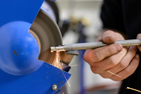 Skilled worker working on metal on a grinding machine - close-up