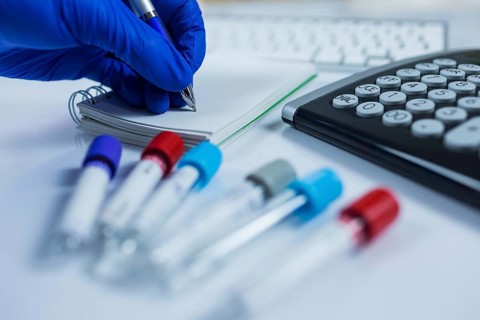 Close up photo of medicine bottles for samples next to computer tablet and computer keyboard in