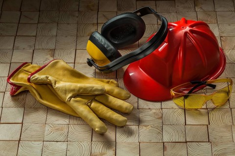 Construction safety tools leather gloves red helmet goggles and earphones on wooden background