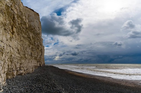 Landscape view of a black rock beach on the Jurassic Coast of England with tall chalkstone cliffs