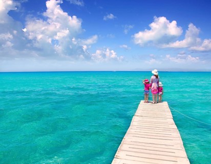 Daughters and mother in jetty on Formentera with turquoise sea
