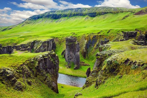 Bizarre shape of cliffs surround the stream with glacial water. The striking canyon in Iceland. The