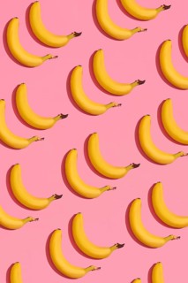Food design. Pattern composition of a pair of bananas lying next to a pink background. Mock up, top