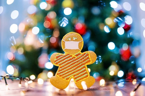 Gingerbread man in a protective icing mask on the table in the light of multi-colored lights on the