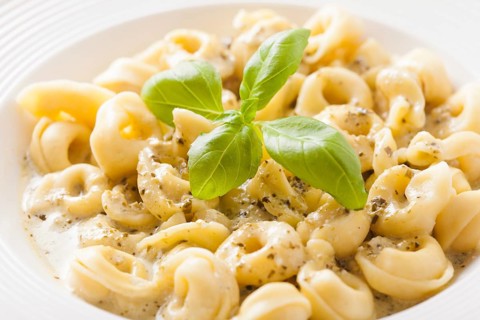 Delicious dish of tortellini with pesto in white plate