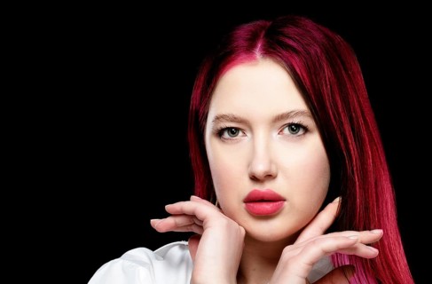 Beautiful girl model with sensual lips and red hair on a black background