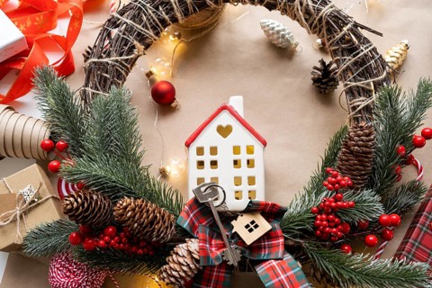 Key to the house with a keychain on a cozy home with a Christmas decor layout. A gift for New Year,