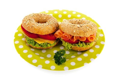Fresh bagels with cheese, vegetables and fish isolated over white background