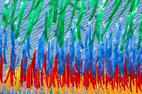 Close up shot of decorative multicolor ribbons waving in the wind at city street holiday, festival