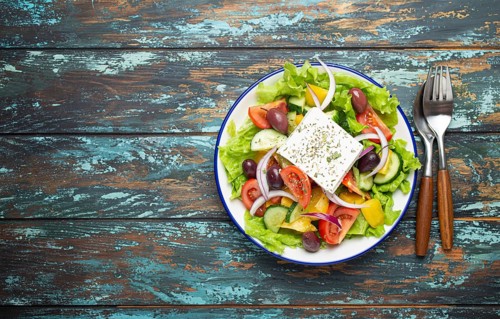 Traditional Greek Salad with Feta Cheese, Tomatoes, Bell Pepper, Cucumbers, Olives, Herbs in white