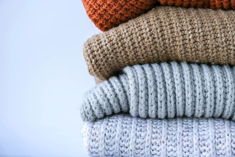 Stack of cozy knitted warm sweater. Sweaters in retro Style. Orange and blue colors. Cozy hygge