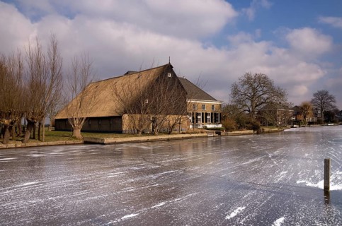 Frozen river the Graafstroom with on the other side a monumental farm in the South Holland village