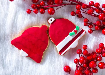 Christmas cookies Xmas red bell shape on white fur background