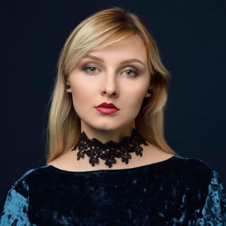 Portrait of the beautiful blonde woman in the blue velvet dress. Shooting in the studio with a dark