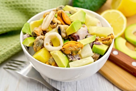 Salad with shrimps, octopus, mussels and calamari with avocado, lettuce, lemon and pineapple in a