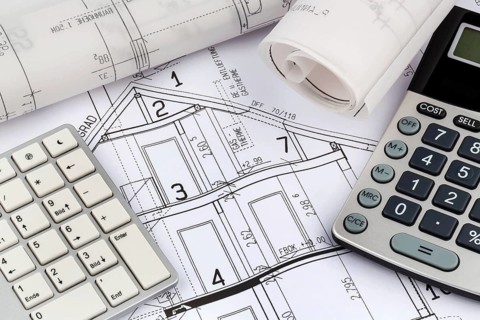 An architect's construction plan with a calculator. Symbolic photo for financing and planning a new