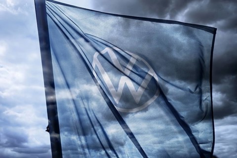 VW sign on the flag of a car dealer in front of a dark sky, symbolic photo VW crisis, photomontage