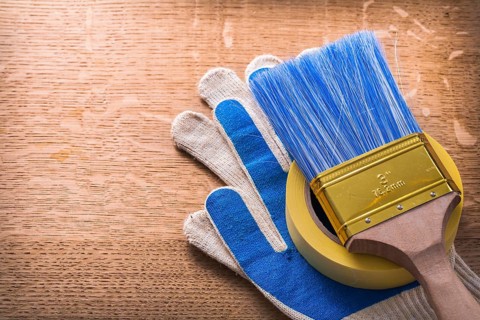 Protective gloves paint brush and duct tape on wooden board construction concept