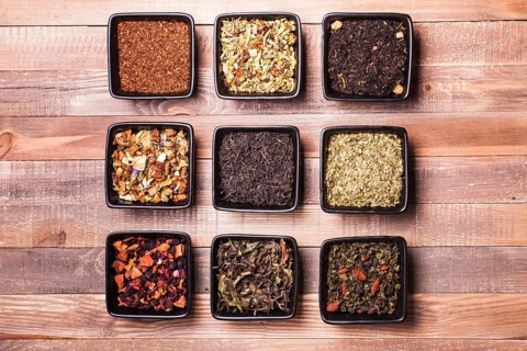 Various tea in a black ceramic bowls on a wooden table