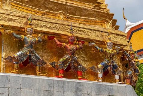 A picture of statues at the base of a golden chedi at the Grand Palace, in Bangkok