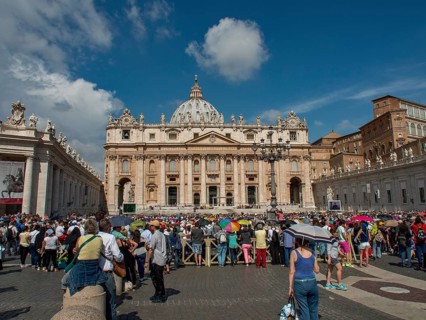St Peter's Basilica with a large crowd in the square in front of it under a clear blue sky, rome,