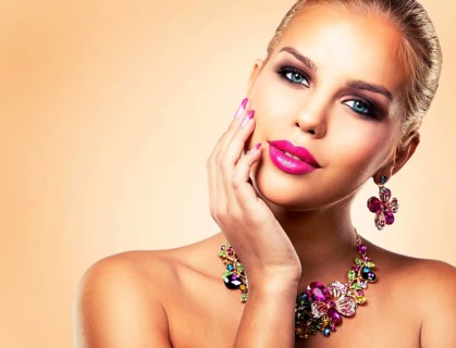 Beautiful woman with dark makeup and pink lipstick posing on beige background wearing flower spring
