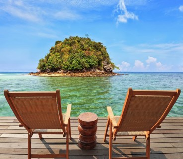 The charming landscape. A green island in a sea bay with emerald water. Two wooden chairs - on a