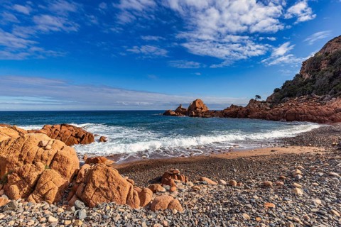 Coastal landscape with red rocks and surf in blue sky and sunshine, Spiaggia di Cala E'Luas,