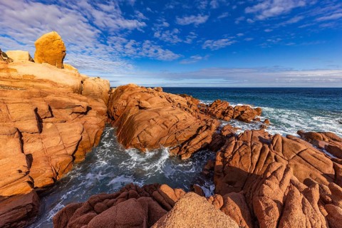 Coastal landscape with red rocks and surf in blue sky and sunshine, Spiaggia di Cala E'Luas,