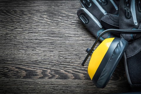 Safety gloves earmuffs on wooden board