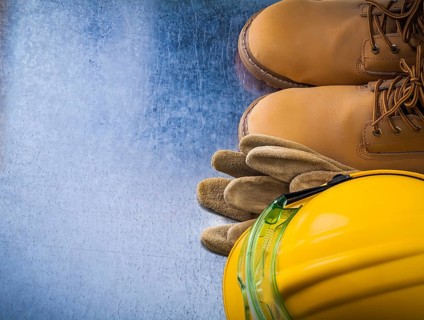 Protective leather gloves waterproof safety boots hard hat and plastic glasses on scratched