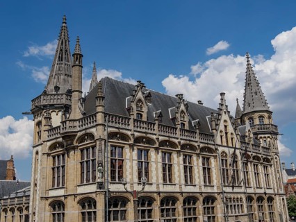 Majestic building with pewter towers and detailed decorations on a clear blue sky, Ghent, Belgium,