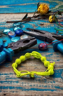 Beads, pliers, and other needlework accessories on outdated turquoise wooden background