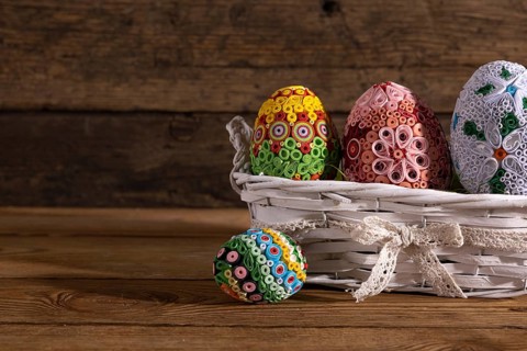 On a background of brown boards set a woven basket with colorful Easter eggs. Easter composition as