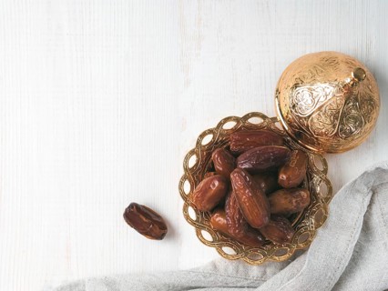 Metal plate of sweet dried dates and linen cloth on gray cement background. Dried dates with copy
