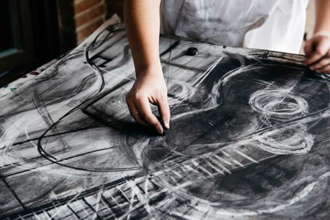 Young female artist painting with charcoal on paper