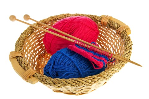 Knitting in blue and red with wooden needles