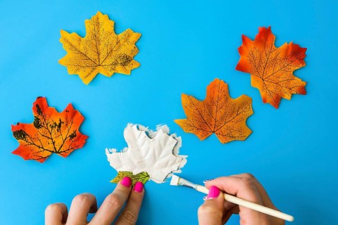 Maple leaf with painted face as decoration for autumn Halloween holiday celebration. Halloween