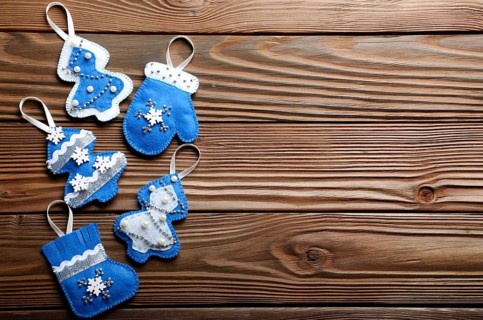 Handmade rustic felt Christmas tree decorations flat laying on wooden table