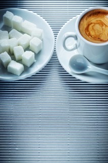 Cup of cappuccino coffee saucer teaspoon sugar cubes on striped background