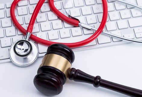 Photo shows an auction hammer and a stethoscope on a computer keyboard
