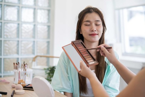 Makeup artist. Professional makeup artist working with beautiful young asian woman applying
