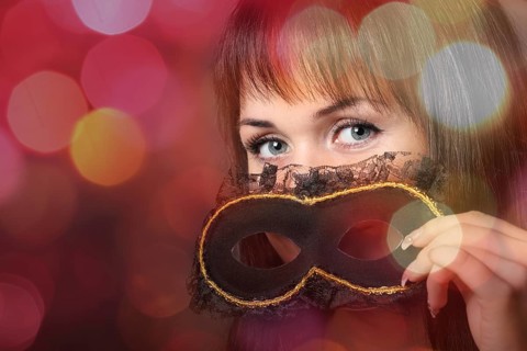 Beautiful young woman in carnival mask over blurred background