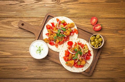 Cooking Traditional Greek Dish Gyros: Pita bread with vegetables, meat, herbs, olives on rustic