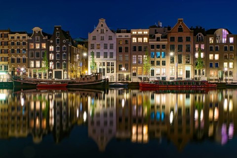 Reflection of the buildings along the canal at night in Amsterdam, Netherlands
