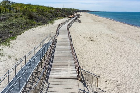 Wooden decking on the sea. Promenade on the sea beach. Deserted sea pier. Walking pier on the beach